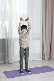 Photo of Little boy exercising with dumbbells at home. Morning routine