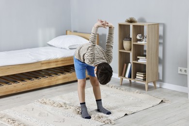 Photo of Little boy exercising at home. Morning routine