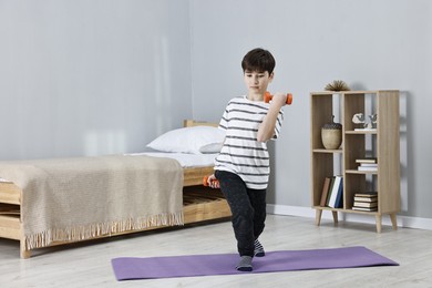 Photo of Little boy exercising with dumbbells at home. Morning routine