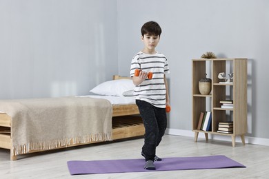 Photo of Little boy exercising with dumbbells at home. Morning routine