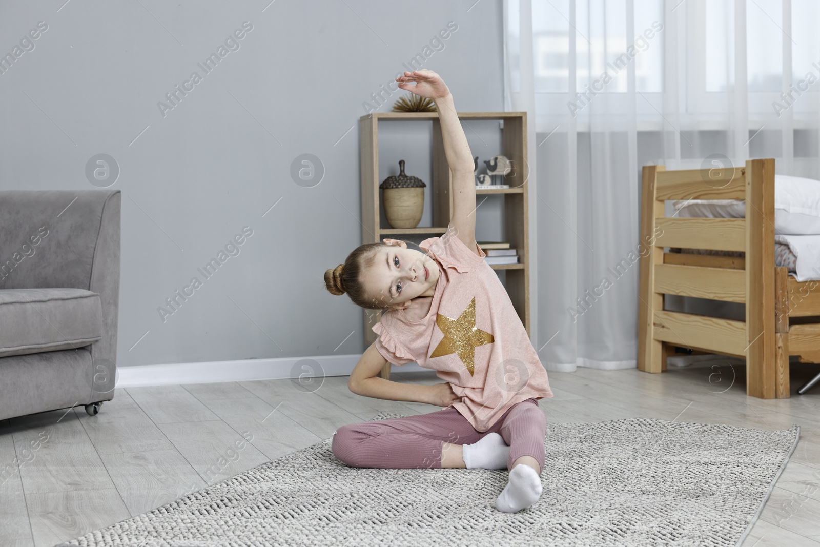 Photo of Little girl exercising at home. Morning routine