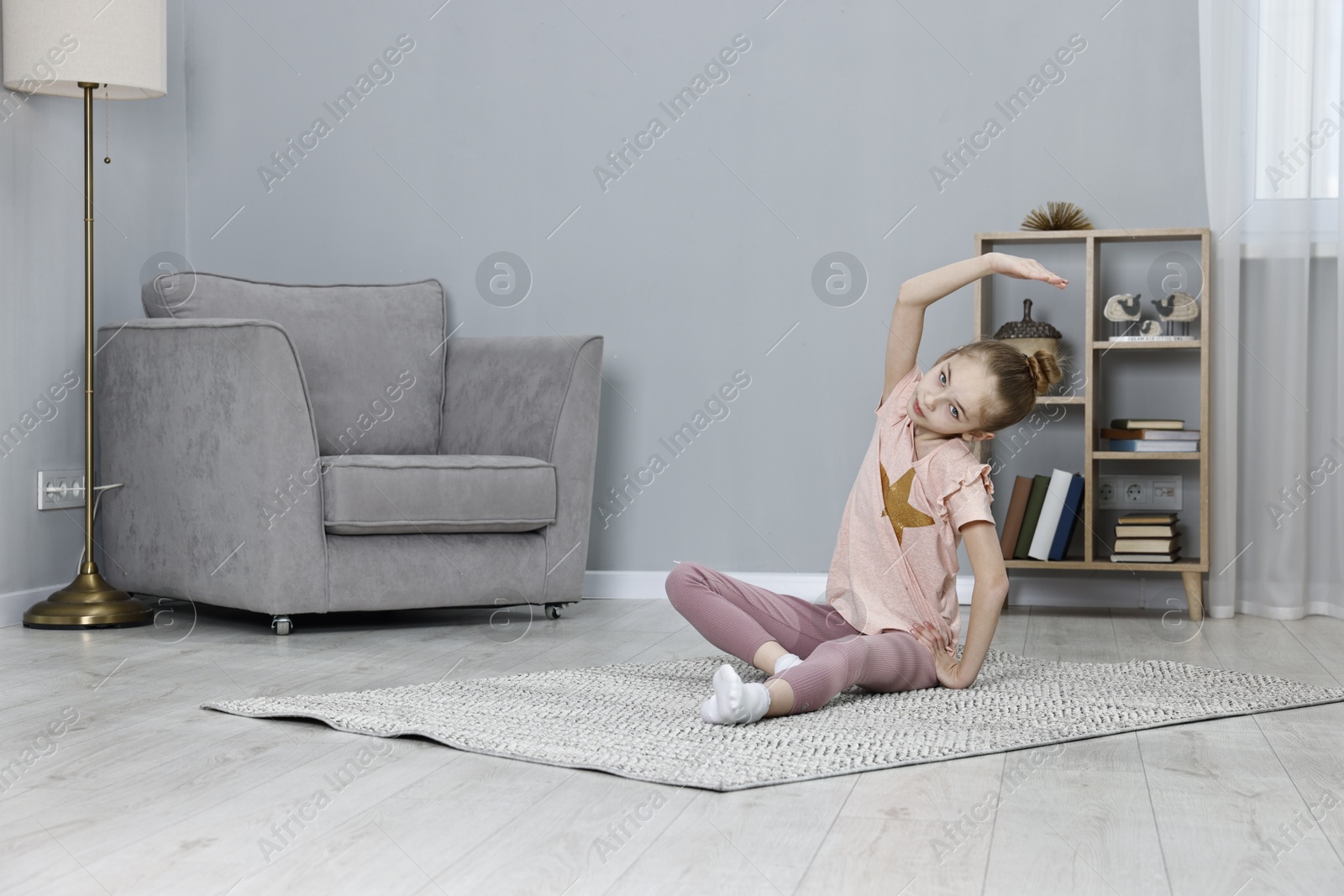 Photo of Little girl exercising at home. Morning routine