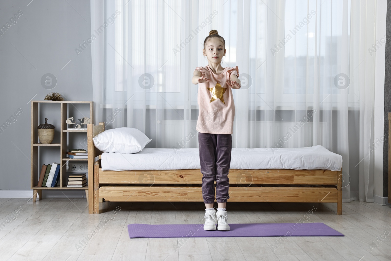 Photo of Little girl exercising at home. Morning routine