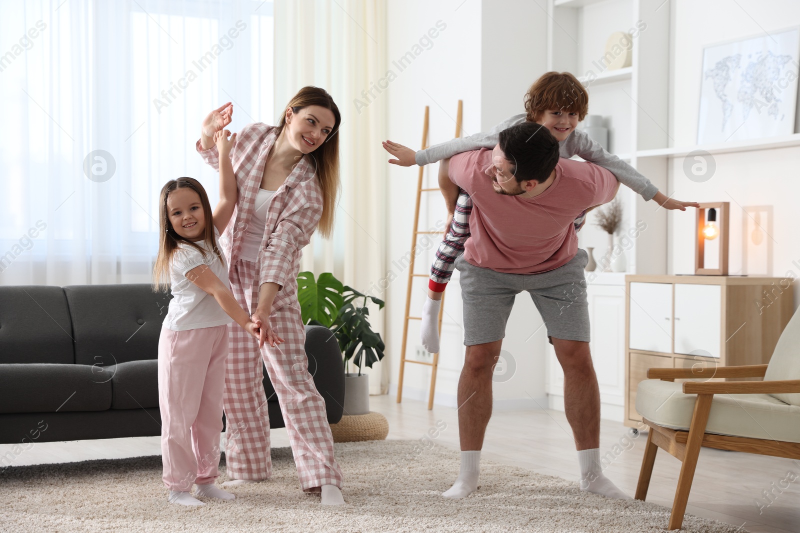 Photo of Happy family wearing stylish pajamas having fun at home