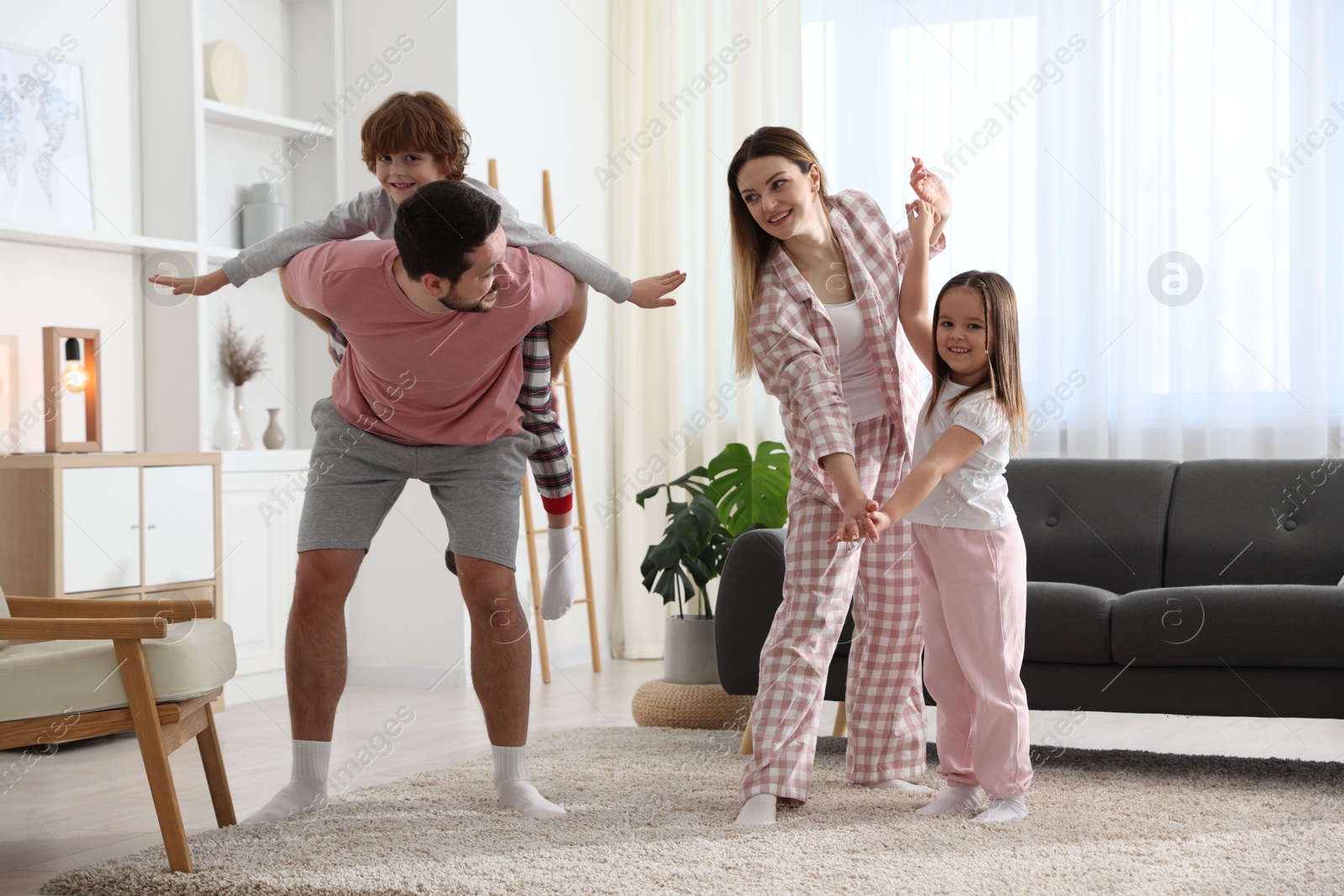 Photo of Happy family wearing stylish pajamas having fun at home