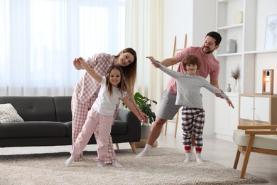 Photo of Happy family wearing stylish pajamas having fun at home