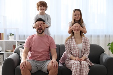 Photo of Happy family wearing stylish pajamas having fun on sofa at home