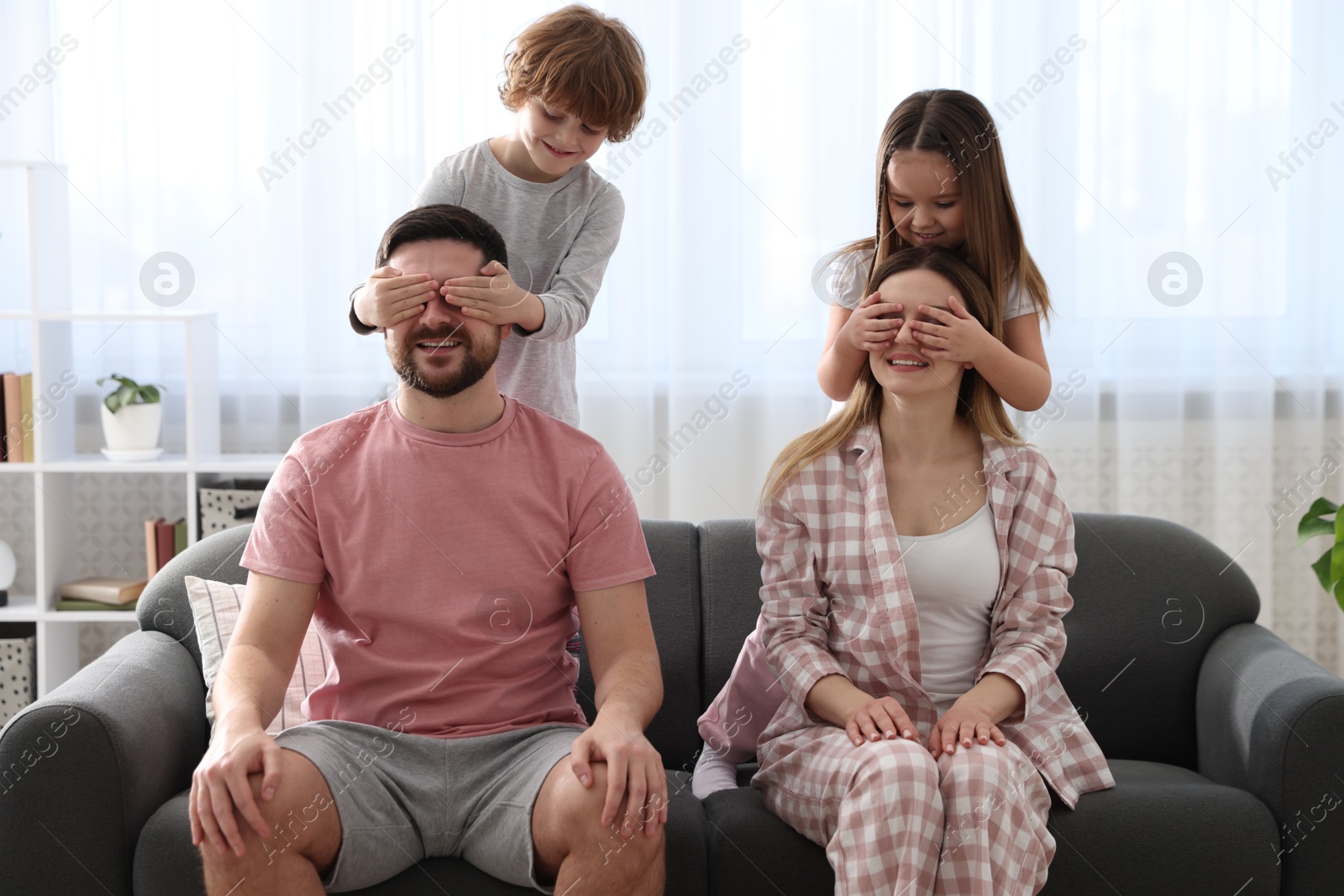 Photo of Happy family wearing stylish pajamas having fun on sofa at home