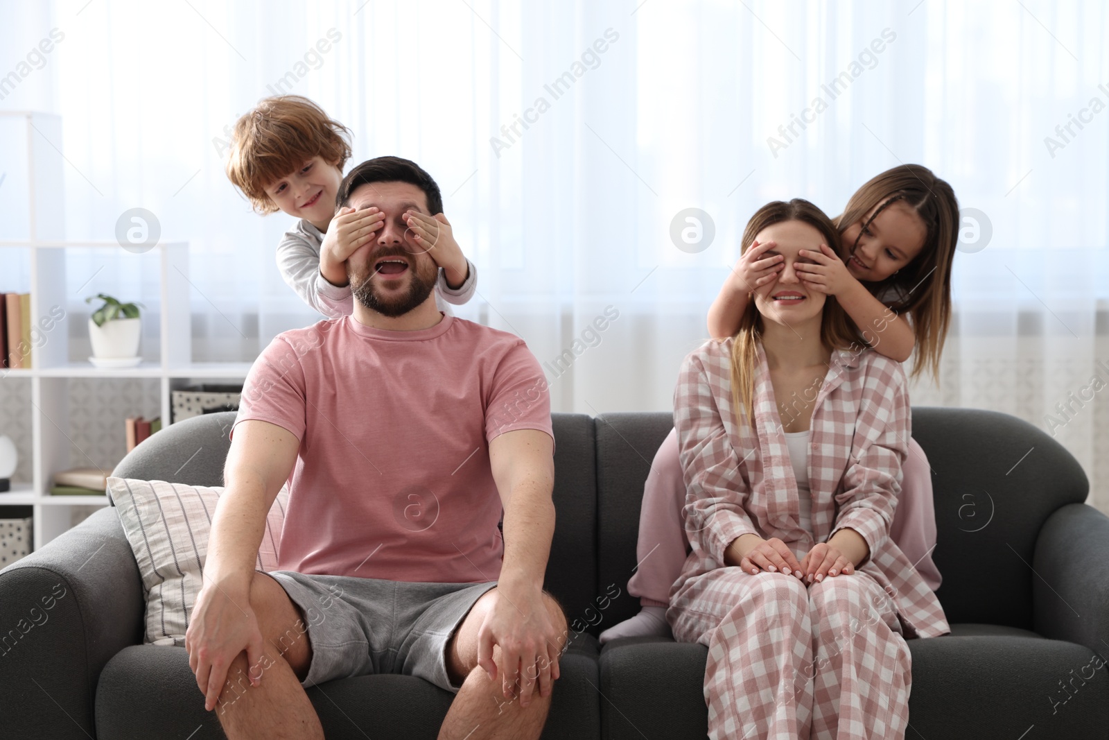 Photo of Happy family wearing stylish pajamas having fun on sofa at home