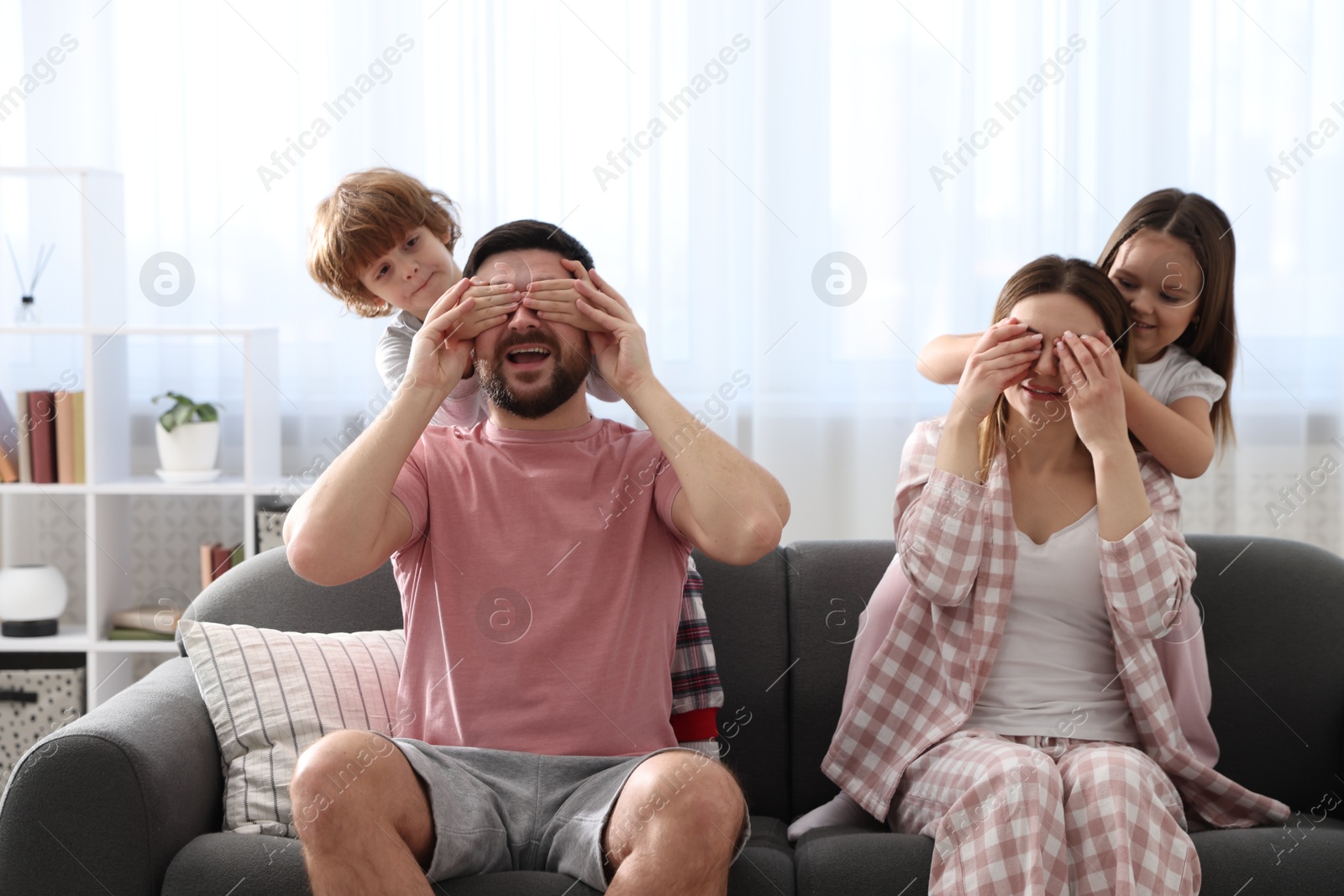 Photo of Happy family wearing stylish pajamas having fun on sofa at home