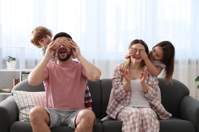 Photo of Happy family wearing stylish pajamas having fun on sofa at home