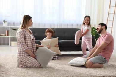 Photo of Happy family wearing pajamas having pillow fight at home