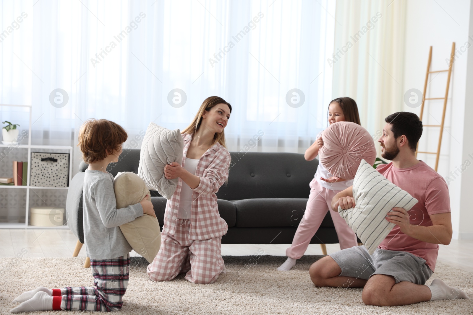 Photo of Happy family wearing pajamas having pillow fight at home