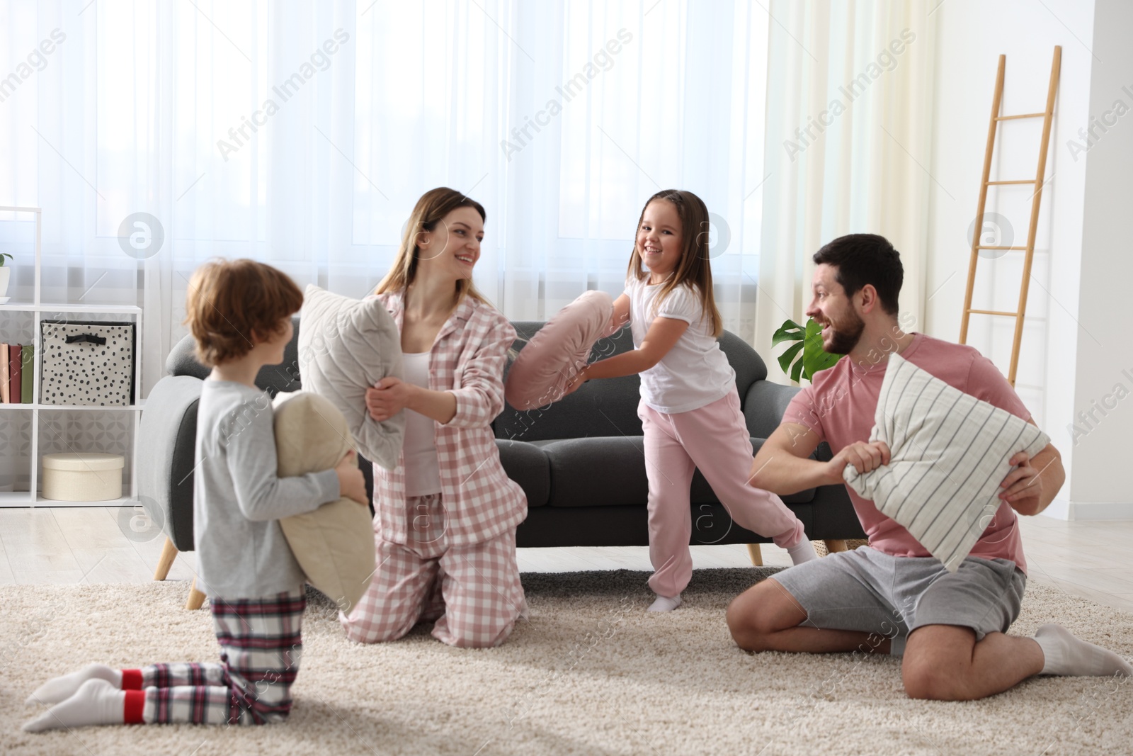 Photo of Happy family wearing pajamas having pillow fight at home