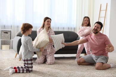 Photo of Happy family wearing pajamas having pillow fight at home