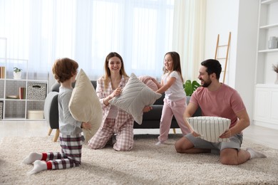 Photo of Happy family wearing pajamas having pillow fight at home