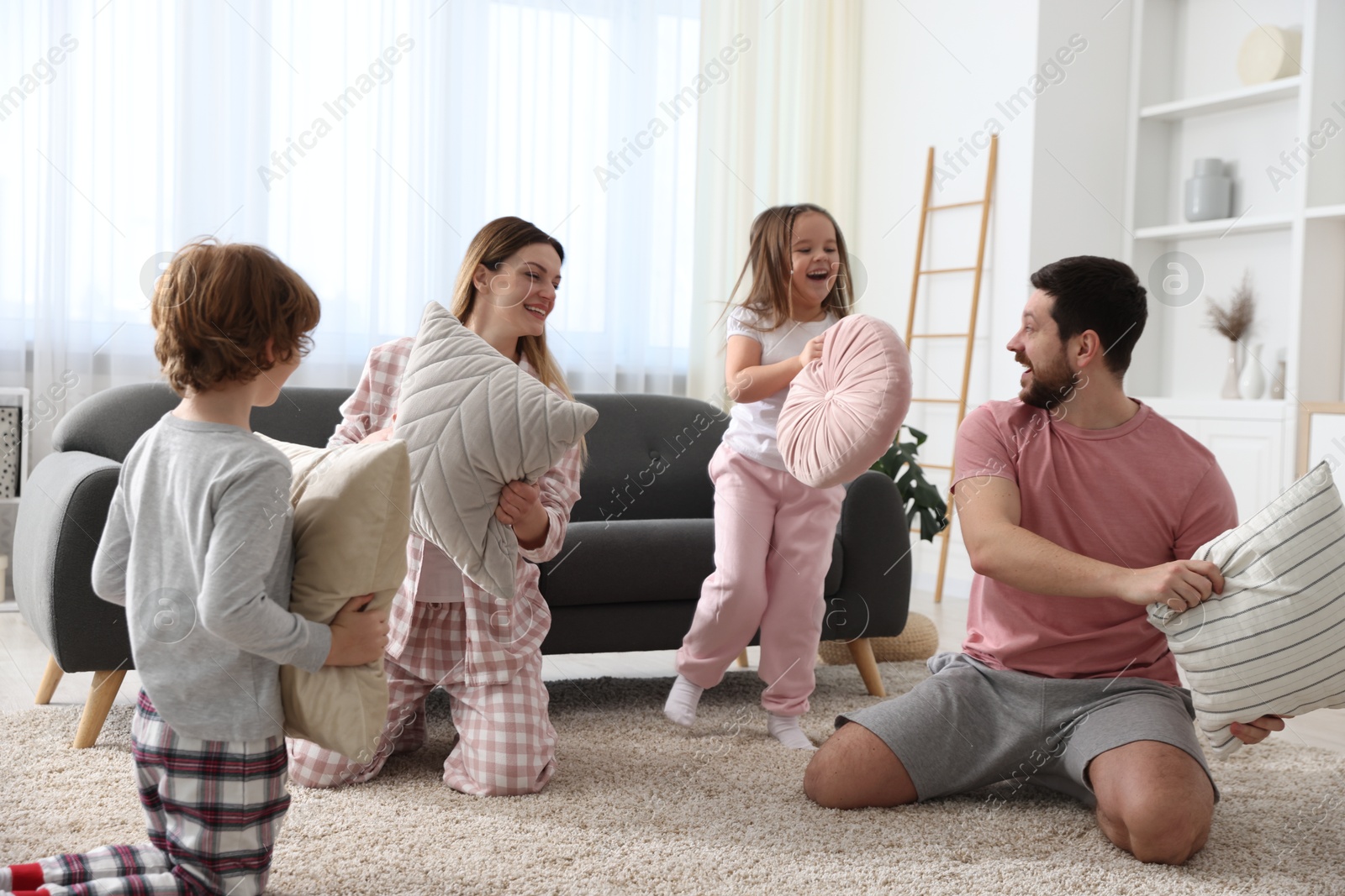 Photo of Happy family wearing pajamas having pillow fight at home