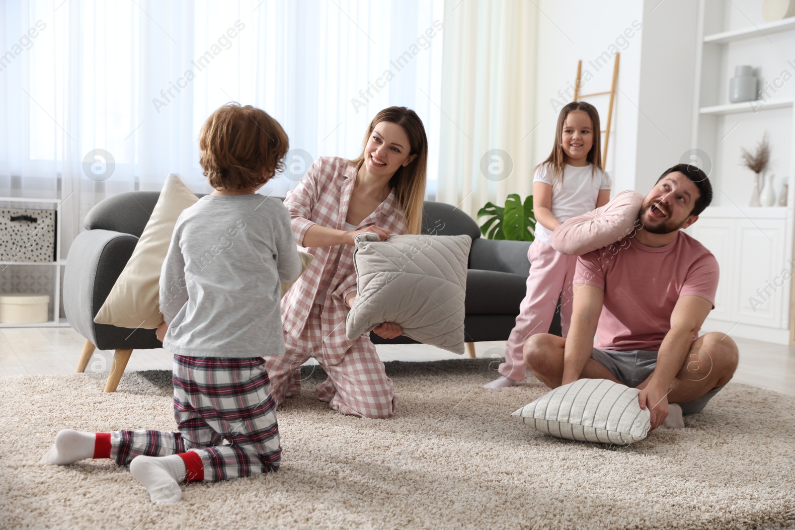 Photo of Happy family wearing pajamas having pillow fight at home