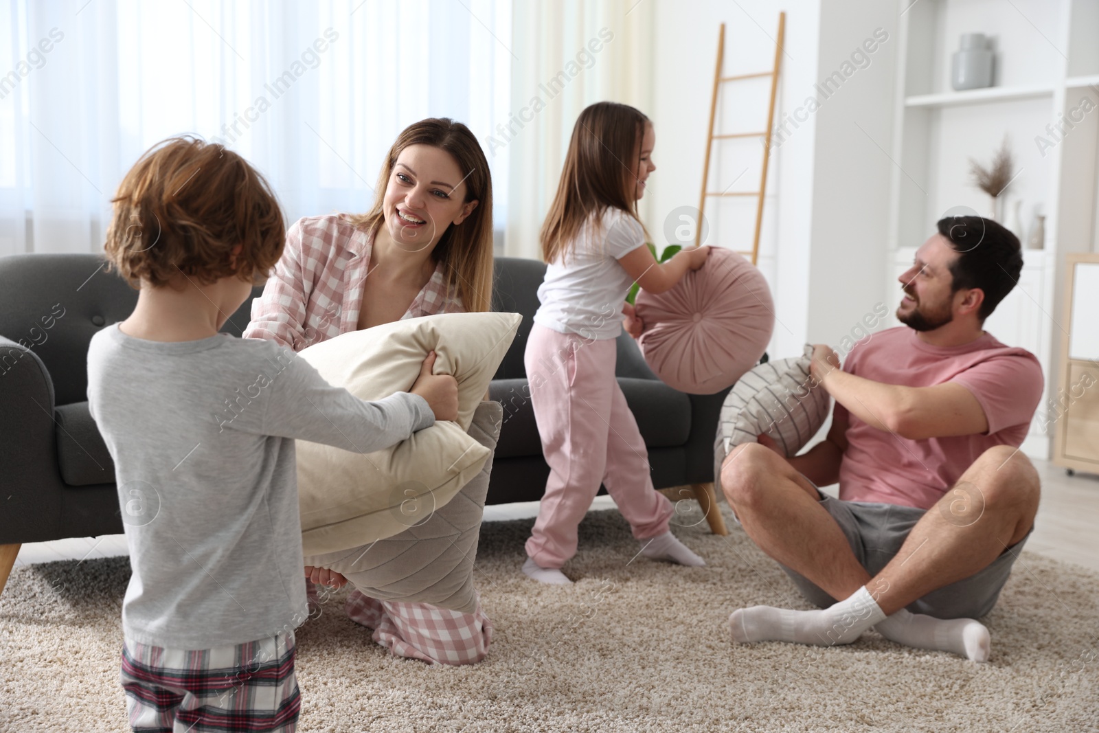 Photo of Happy family wearing pajamas having pillow fight at home