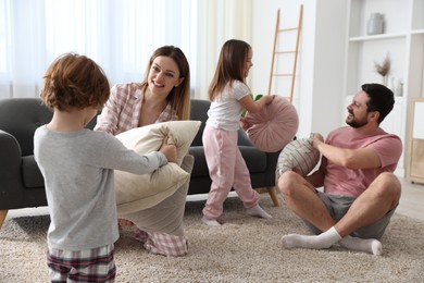 Photo of Happy family wearing pajamas having pillow fight at home