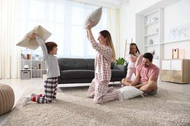 Photo of Happy family wearing pajamas having pillow fight at home