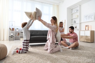 Photo of Happy family wearing pajamas having pillow fight at home