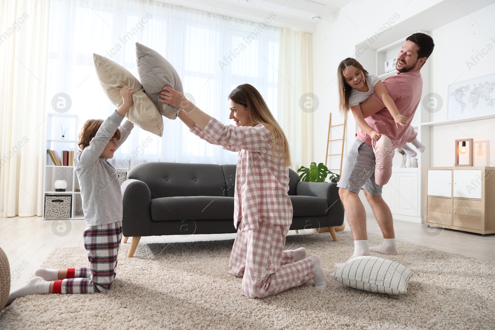 Photo of Happy family wearing pajamas having pillow fight at home