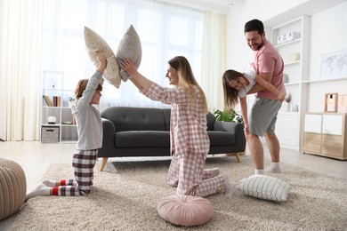 Photo of Happy family wearing pajamas having pillow fight at home