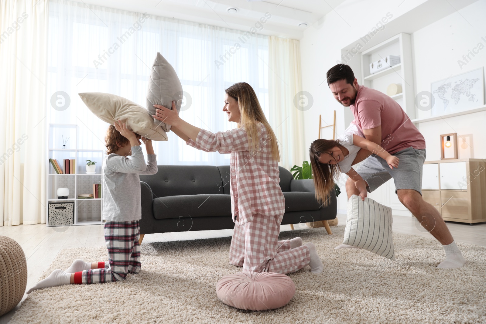 Photo of Happy family wearing pajamas having pillow fight at home