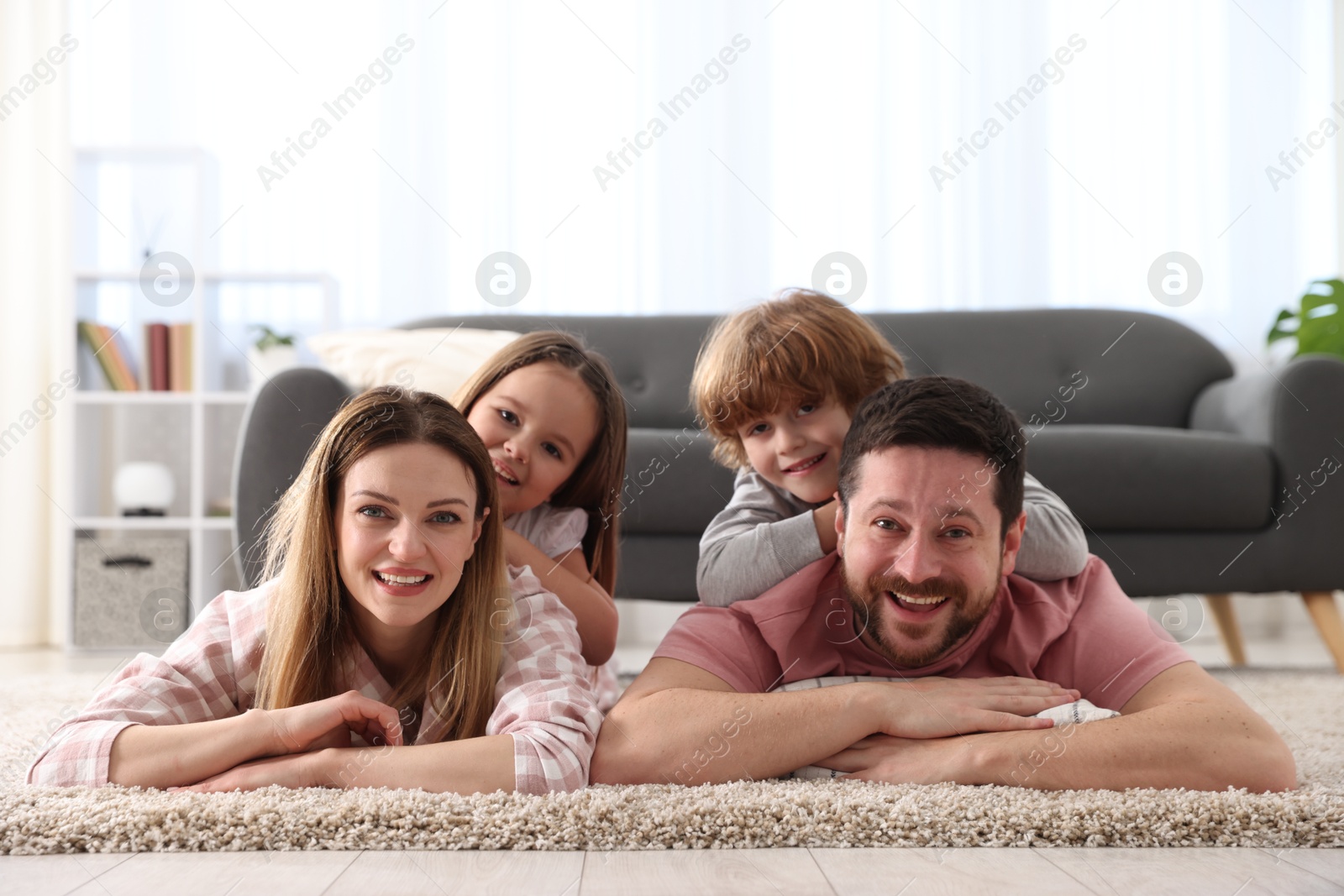 Photo of Family portrait of happy parents and their children wearing stylish pajamas on floor at home