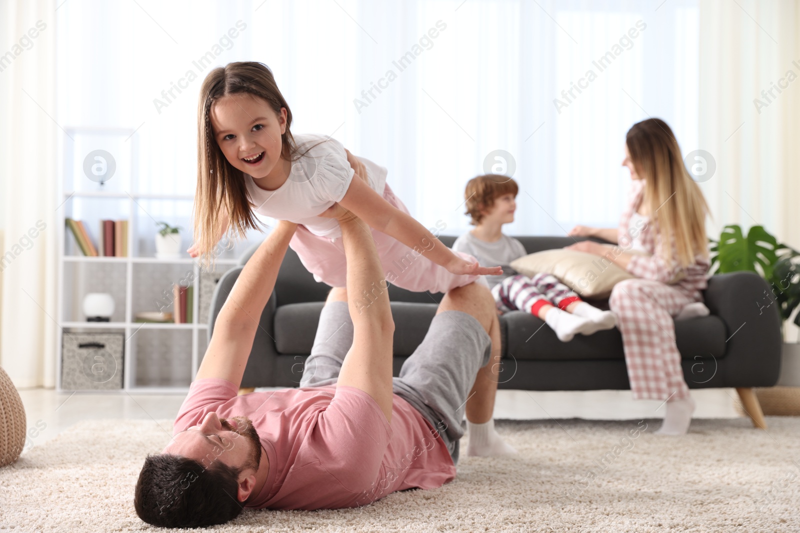 Photo of Happy family wearing stylish pajamas having fun at home, selective focus