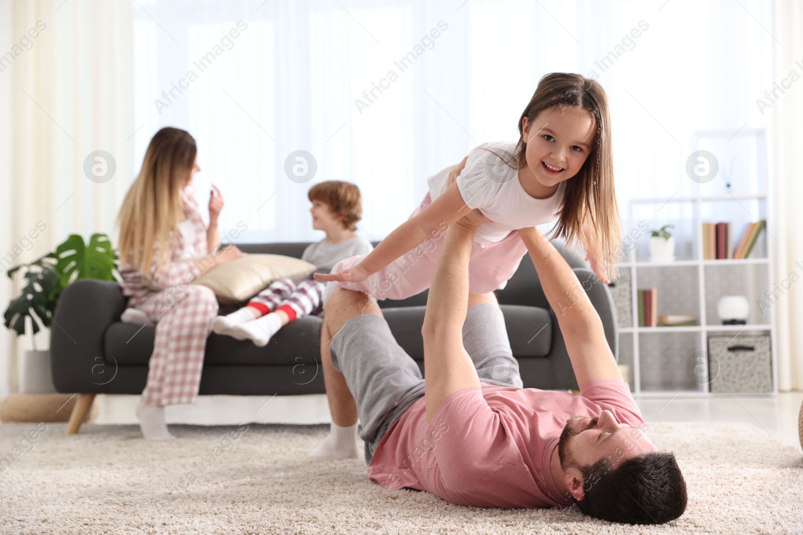 Photo of Happy family wearing stylish pajamas having fun at home, selective focus