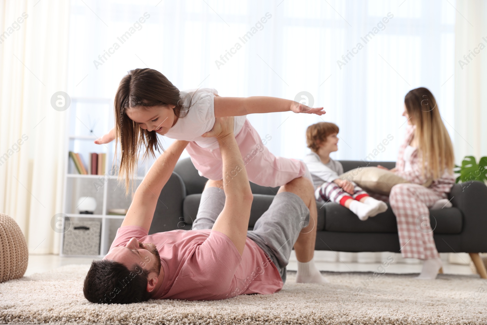 Photo of Happy family wearing stylish pajamas having fun at home, selective focus