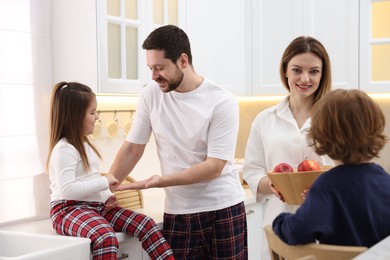 Photo of Happy family wearing stylish pajamas spending time together in kitchen