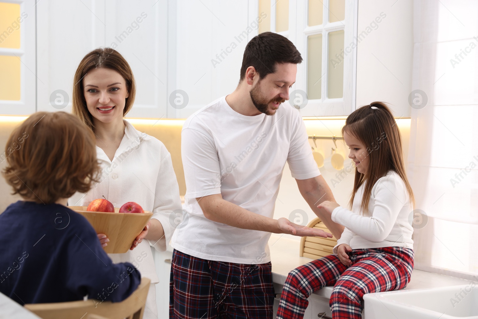 Photo of Happy family wearing stylish pajamas spending time together in kitchen