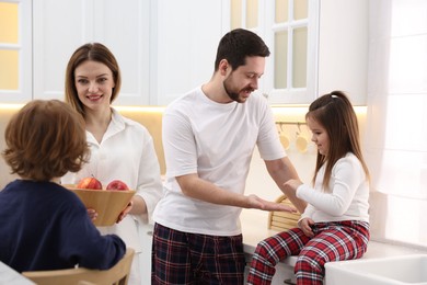 Photo of Happy family wearing stylish pajamas spending time together in kitchen