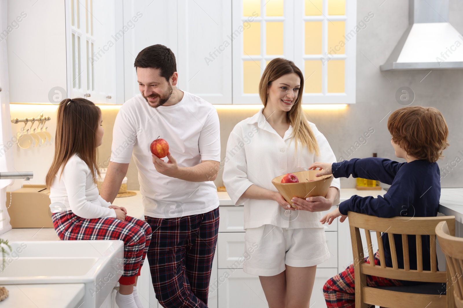 Photo of Happy family wearing stylish pajamas spending time together in kitchen