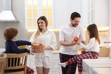 Photo of Happy family wearing stylish pajamas spending time together in kitchen