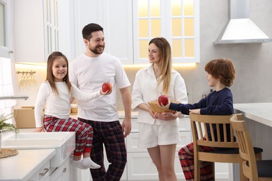 Happy family wearing stylish pajamas spending time together in kitchen