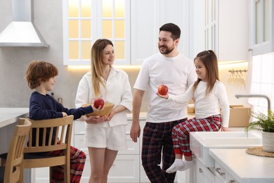 Photo of Happy family wearing stylish pajamas spending time together in kitchen