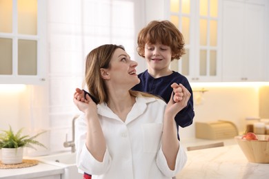 Photo of Smiling woman and her son wearing stylish pajamas in kitchen