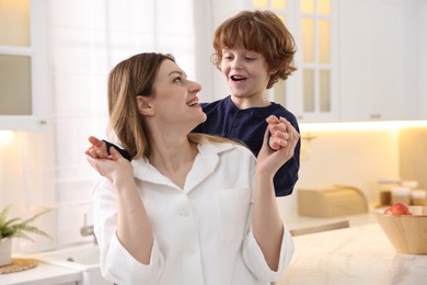 Photo of Smiling woman and her son wearing stylish pajamas in kitchen