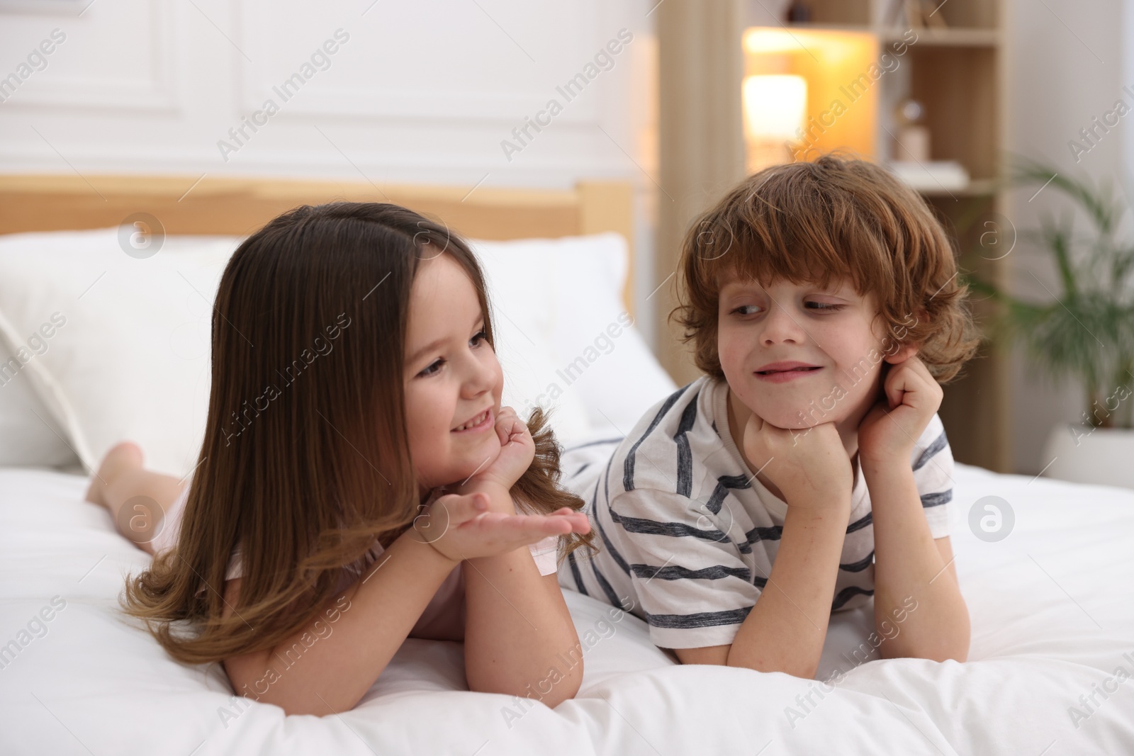 Photo of Happy children wearing pajamas on bed at home