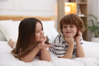 Photo of Happy children wearing pajamas on bed at home