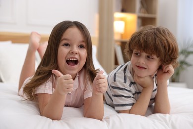 Photo of Happy children wearing pajamas on bed at home