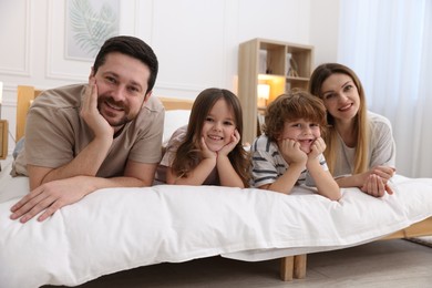 Photo of Family portrait of happy parents and their children wearing pajamas on bed at home