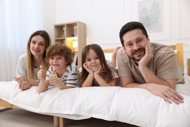 Photo of Family portrait of happy parents and their children wearing pajamas on bed at home