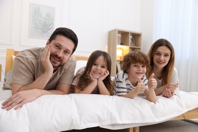 Photo of Family portrait of happy parents and their children wearing pajamas on bed at home