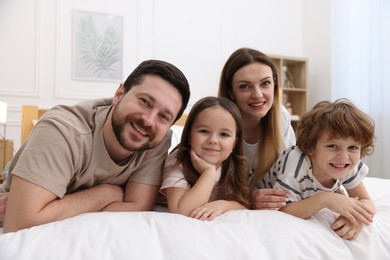 Photo of Family portrait of happy parents and their children wearing pajamas on bed at home