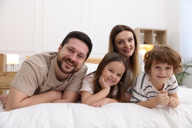 Photo of Family portrait of happy parents and their children wearing pajamas on bed at home